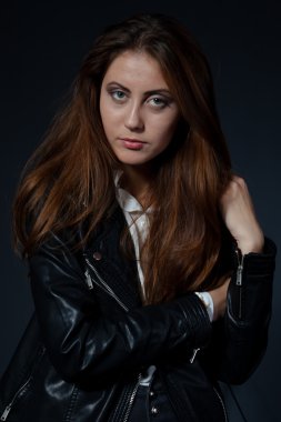 siyah arka plan üzerine siyah deri ceketli çekici genç kadın