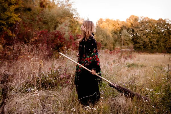 Menina bonita em vestido preto em pé entre folhas coloridas — Fotografia de Stock