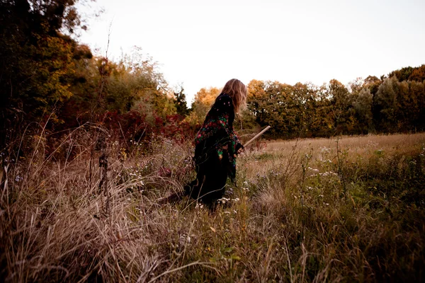 葉の間に立ってカラフルな黒のドレスで美しい少女 — ストック写真