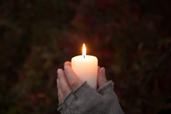 Mani di preghiera con candela su sfondo scuro — Foto Stock