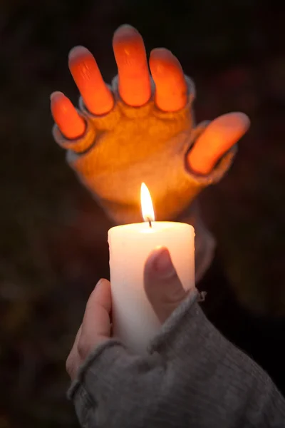 Mani di preghiera con candela su sfondo scuro — Foto Stock