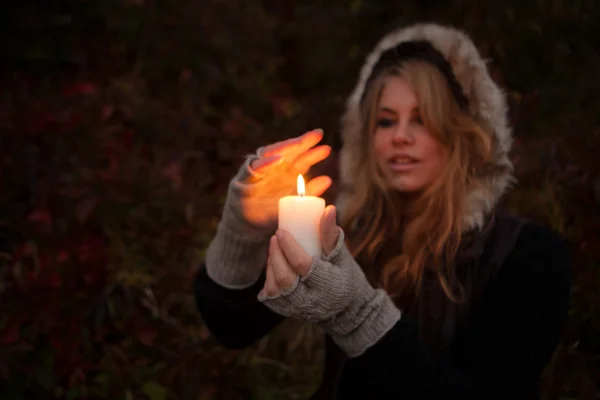 Mladá žena hledá na svíčku — Stock fotografie