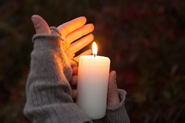 Mladá žena hledá svíčka Praying Hands s svíčka v tmavém pozadí — Stock fotografie