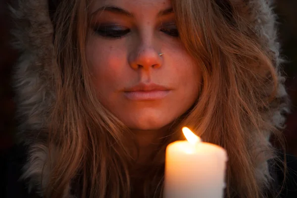 Jeune femme regardant vers une bougie — Photo