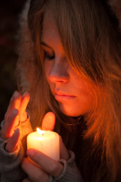 Jeune femme regardant vers une bougie — Photo