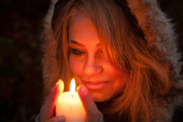 Jeune femme regardant vers une bougie — Photo