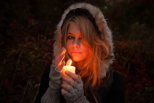 Mladá žena hledá na svíčku — Stock fotografie