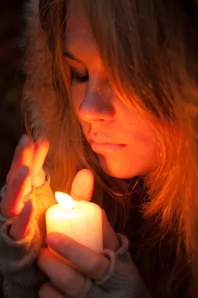 Jeune femme regardant vers une bougie — Photo