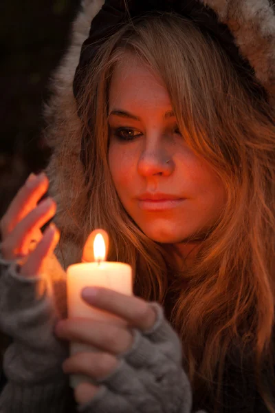 Jonge vrouw op zoek naar een kaars — Stockfoto