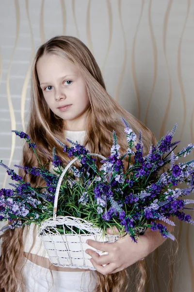 Kleines blondes Mädchen im weißen Kleid mit violetten Blüten — Stockfoto