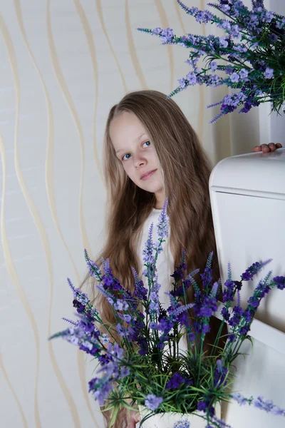 Kleines blondes Mädchen im weißen Kleid mit violetten Blüten — Stockfoto