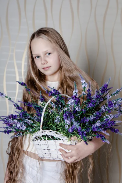 Kleines blondes Mädchen im weißen Kleid mit violetten Blüten — Stockfoto