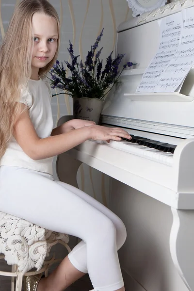 Porträt eines kleinen Mädchens im weißen Kleid, das Klavier spielt — Stockfoto