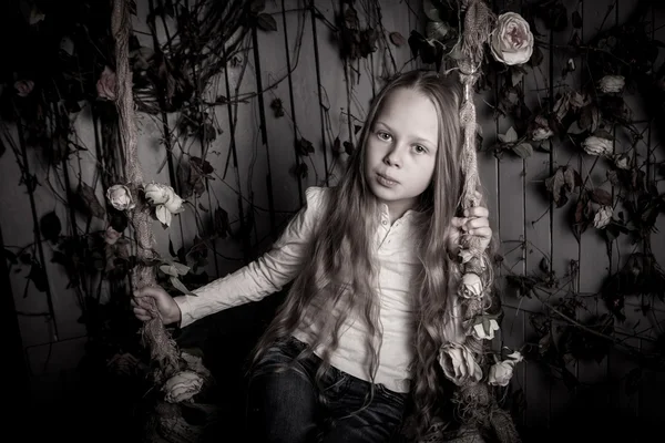Pretty blond preteen girl sitting with flowers — Stock Photo, Image