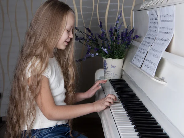 Портрет маленькой девочки в белом платье, играющей на пианино . — стоковое фото