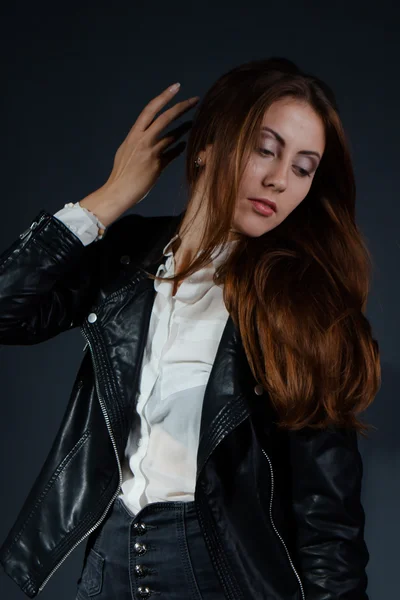 Mujer joven glamorosa en chaqueta de cuero negro sobre fondo negro — Foto de Stock
