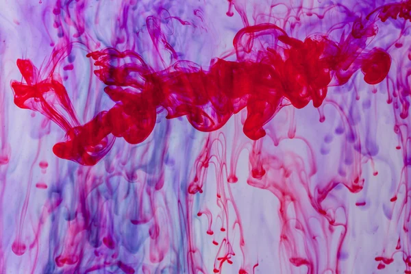 Röda och violetta vätska i vatten gör abstrakta form — Stockfoto