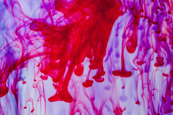 Röda och violetta vätska i vatten gör abstrakta form — Stockfoto
