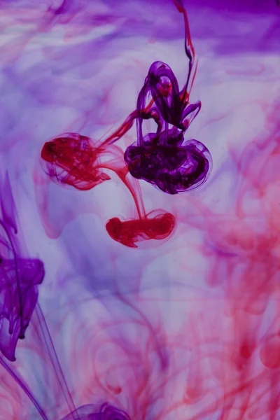 Red and violet liquid in water making abstract form — Stock Photo, Image