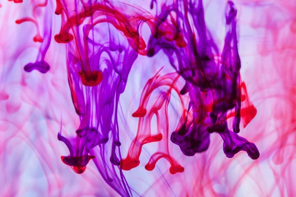 Červené a fialové kapalina ve vodě dělat abstraktní forma — Stock fotografie