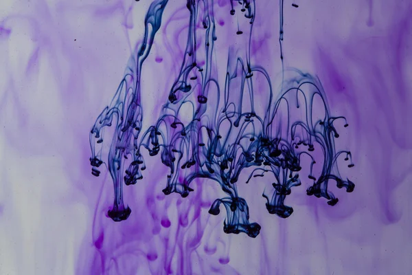 Liquide bleu et violet dans l'eau faisant des formes abstraites — Photo