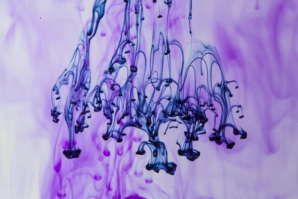 Liquide bleu et violet dans l'eau faisant des formes abstraites — Photo
