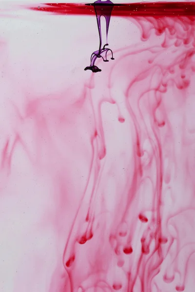 Líquido azul e violeta em água fazendo formas abstratas — Fotografia de Stock