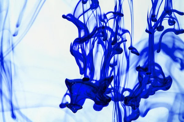 Blaue und violette Flüssigkeit im Wasser, die abstrakte Formen bildet — Stockfoto