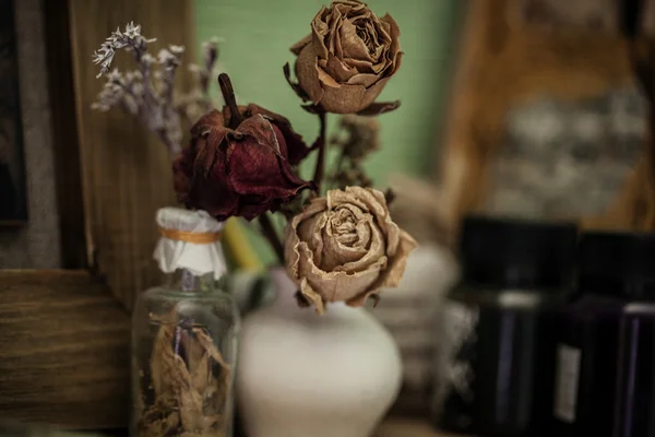 Vintage style still life  with three dried roses and bottle — Stock Photo, Image