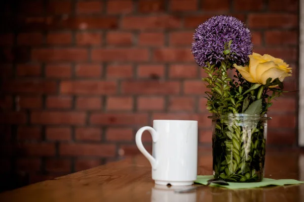 Tazza di caffè e bellissimi fiori su sfondo di legno — Foto Stock