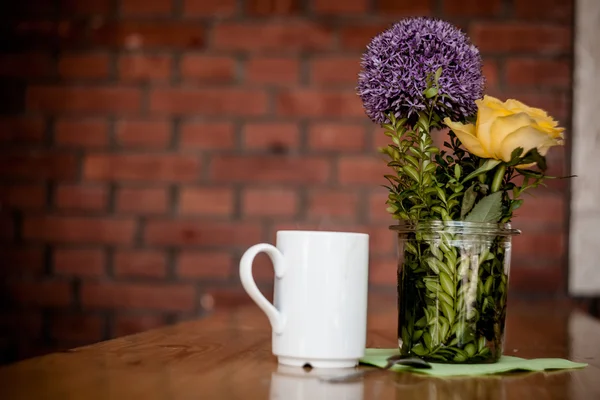 Tazza di caffè e bellissimi fiori su sfondo di legno — Foto Stock