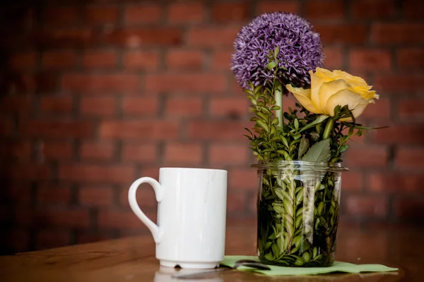 Tazza di caffè e bellissimi fiori su sfondo di legno — Foto Stock