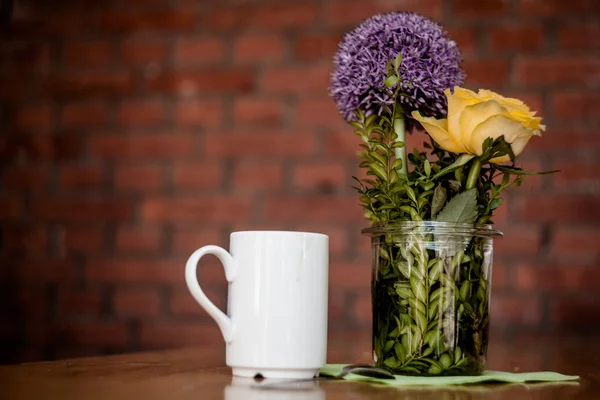 Tazza di caffè e bellissimi fiori su sfondo di legno — Foto Stock