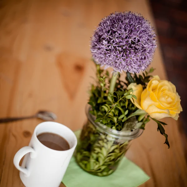 Чашка кави і красиві квіти на дерев'яному фоні — стокове фото
