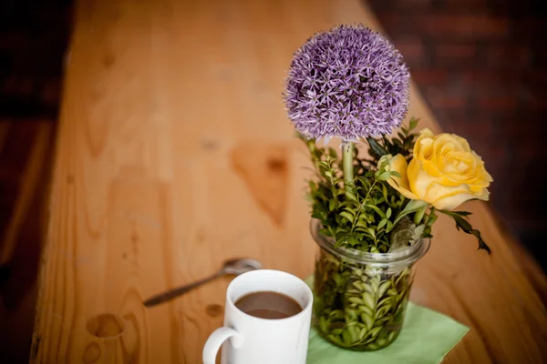 Kopp kaffe och vackra blommor på trä bakgrund — Stockfoto