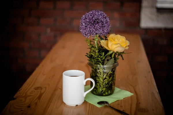 Tazza di caffè e bellissimi fiori su sfondo di legno — Foto Stock
