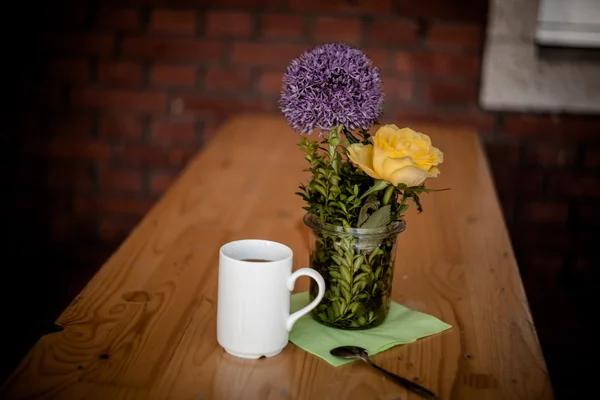 Tazza di caffè e bellissimi fiori su sfondo di legno — Foto Stock