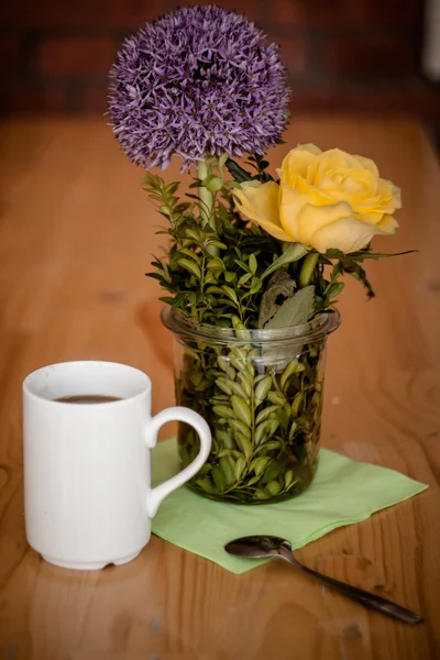 Šálek kávy a krásné květiny na dřevěné pozadí — Stock fotografie