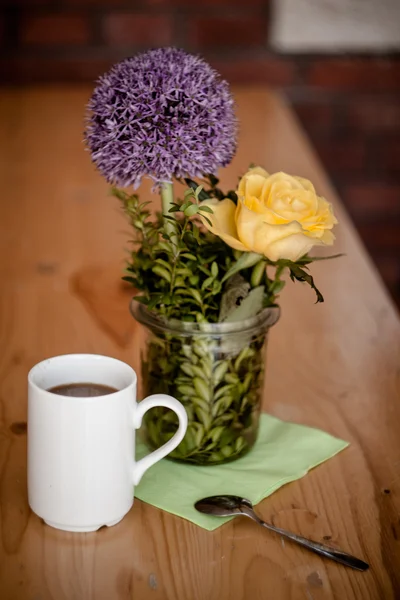 Kopp kaffe och vackra blommor på trä bakgrund — Stockfoto