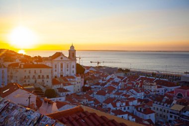 Lizbon 'un ikonik kırmızı kiremitli çatılarının çarpıcı bir panoramik gün doğumu görüntüsü, güneş doğarken tarihi mimari