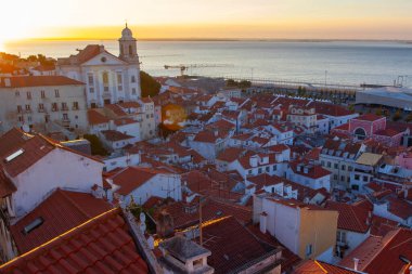 Lizbon 'un ikonik kırmızı kiremitli çatılarının çarpıcı bir panoramik gün doğumu görüntüsü, güneş doğarken tarihi mimari