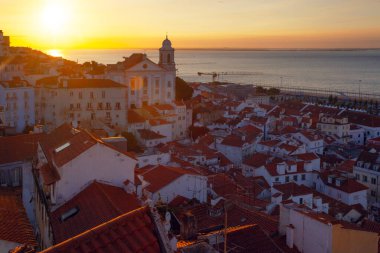 Lizbon 'un ikonik kırmızı kiremitli çatılarının çarpıcı bir panoramik gün doğumu görüntüsü, güneş doğarken tarihi mimari