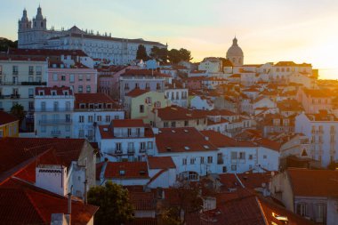 Lizbon 'un ikonik kırmızı kiremitli çatılarının çarpıcı bir panoramik gün doğumu görüntüsü, güneş doğarken tarihi mimari