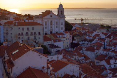 Lizbon 'un ikonik kırmızı kiremitli çatılarının çarpıcı bir panoramik gün doğumu görüntüsü, güneş doğarken tarihi mimari