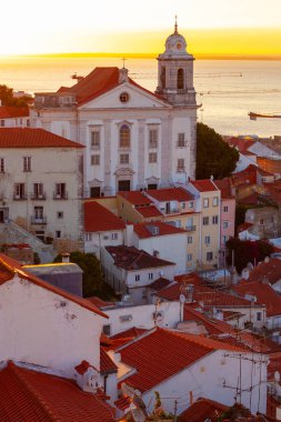 Lizbon, Portekiz - 27 Temmuz 2025: Lizbon 'un ikonik kırmızı kiremitli çatılarının çarpıcı bir panoramik gün doğumu görüntüsü, gündoğumu sırasındaki tarihi mimari
