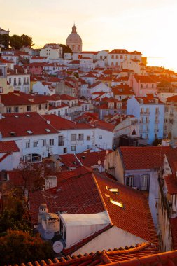 Lizbon, Portekiz - 27 Temmuz 2025: Lizbon 'un ikonik kırmızı kiremitli çatılarının çarpıcı bir panoramik gün doğumu görüntüsü, gündoğumu sırasındaki tarihi mimari