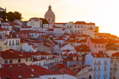 Lizbon, Portekiz - 27 Temmuz 2025: Lizbon 'un ikonik kırmızı kiremitli çatılarının çarpıcı bir panoramik gün doğumu görüntüsü, gündoğumu sırasındaki tarihi mimari