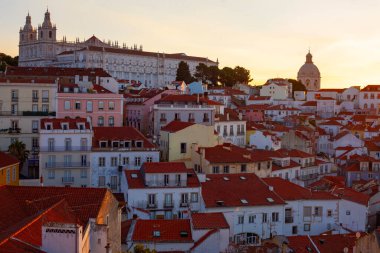 Lizbon, Portekiz - 27 Temmuz 2025: Lizbon 'un ikonik kırmızı kiremitli çatılarının çarpıcı bir panoramik gün doğumu görüntüsü, gündoğumu sırasındaki tarihi mimari
