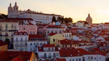 Lizbon, Portekiz - 27 Temmuz 2025: Lizbon 'un ikonik kırmızı kiremitli çatılarının çarpıcı bir panoramik gün doğumu görüntüsü, gündoğumu sırasındaki tarihi mimari