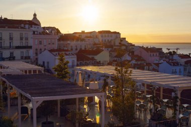 Lizbon, Portekiz - 27 Temmuz 2025: Lizbon 'un ikonik kırmızı kiremitli çatılarının çarpıcı bir panoramik gün doğumu görüntüsü, gündoğumu sırasındaki tarihi mimari